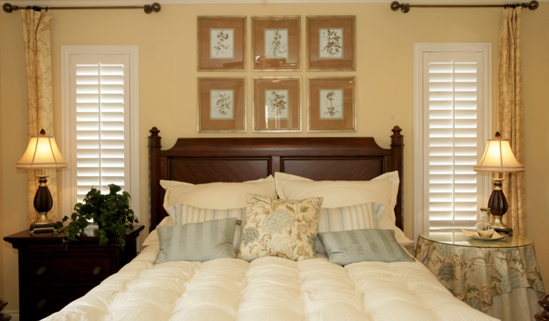Beige bedroom with white plantation shutters covering windows in Virginia Beach 